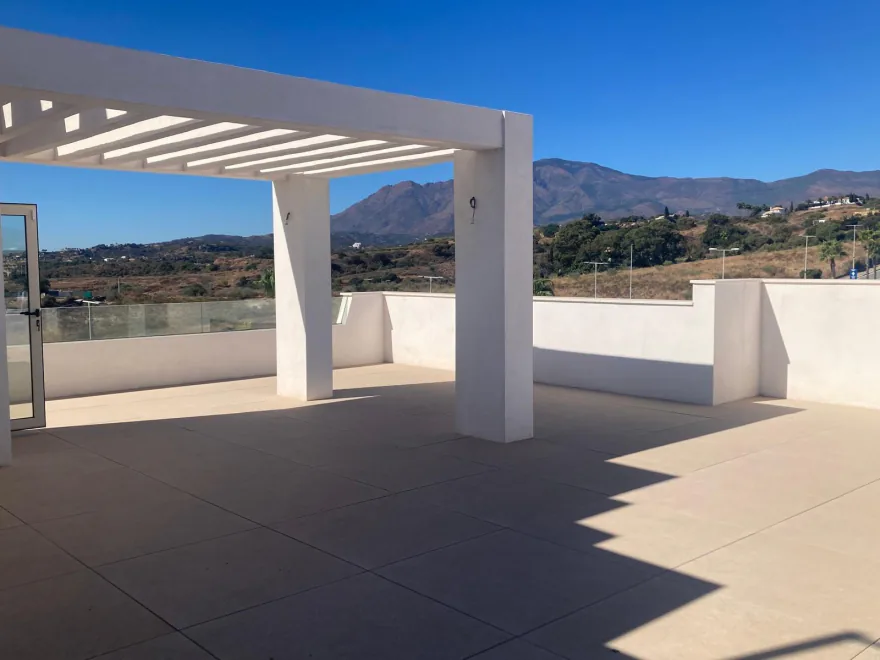 Solárium con pérgola blanca y Sierra Bermeja al fondo, en Selwo